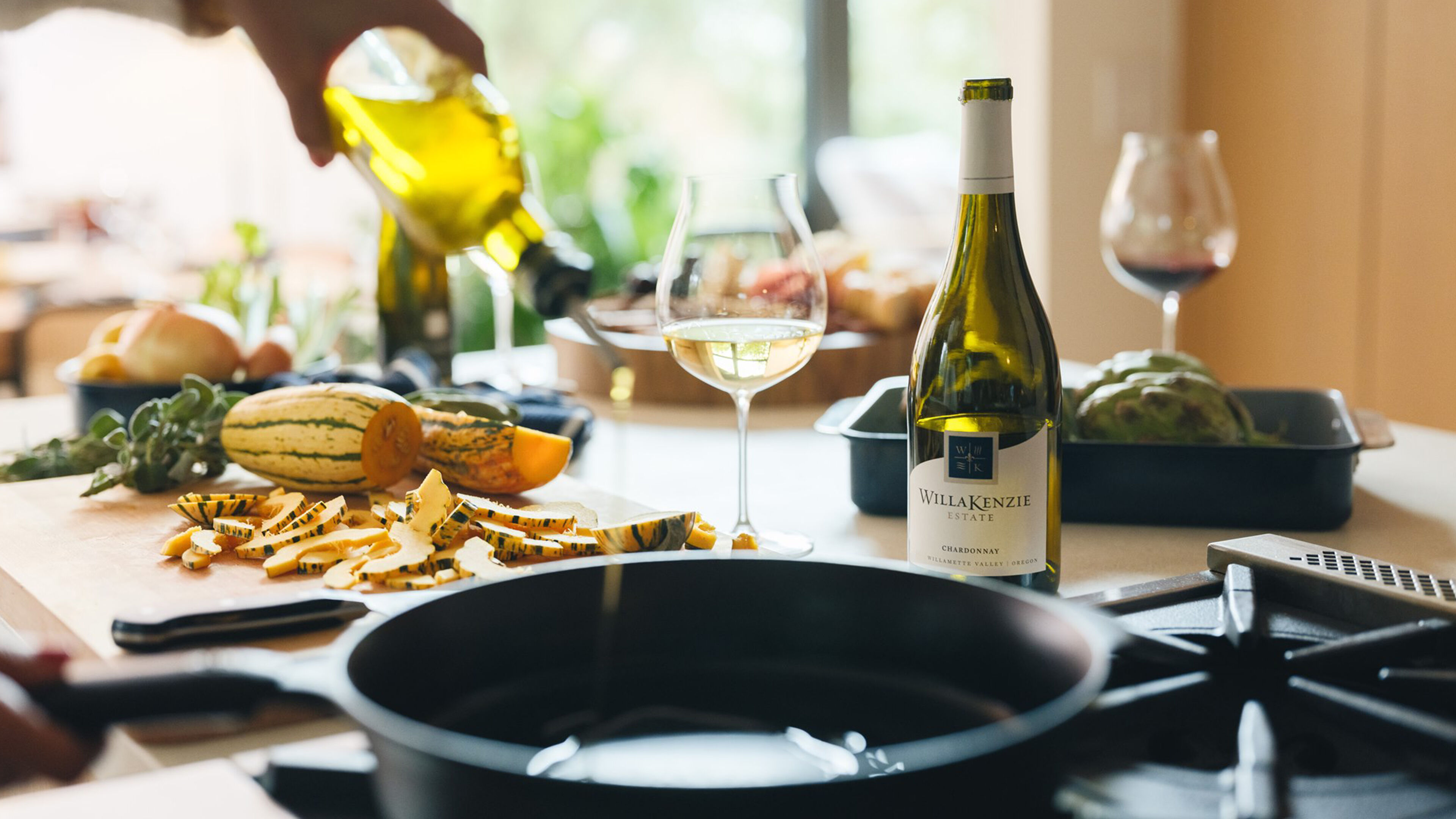 Kitchen counter with vegetables and wine with glasses.